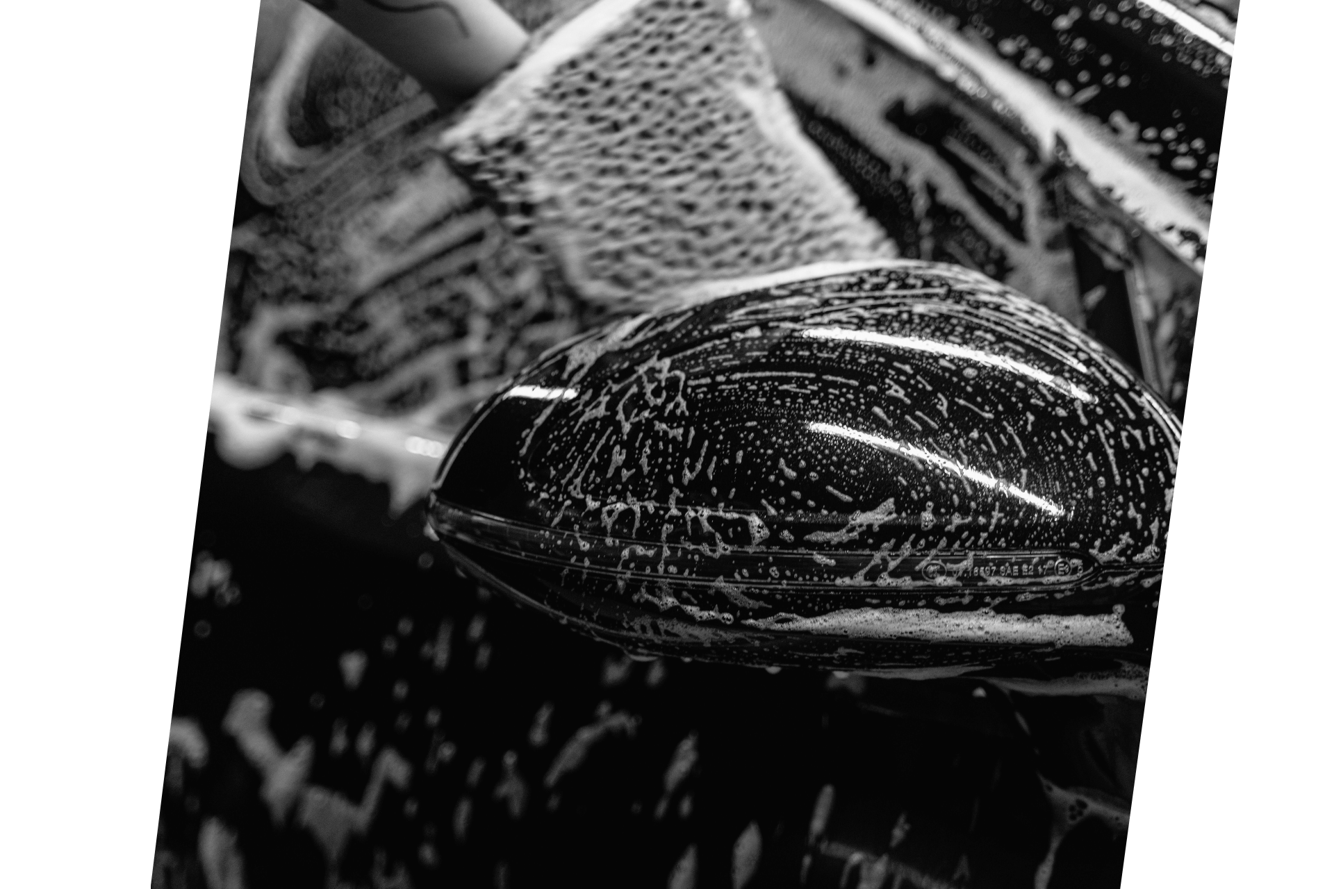 Black and white image of car being rubbed with a sponge